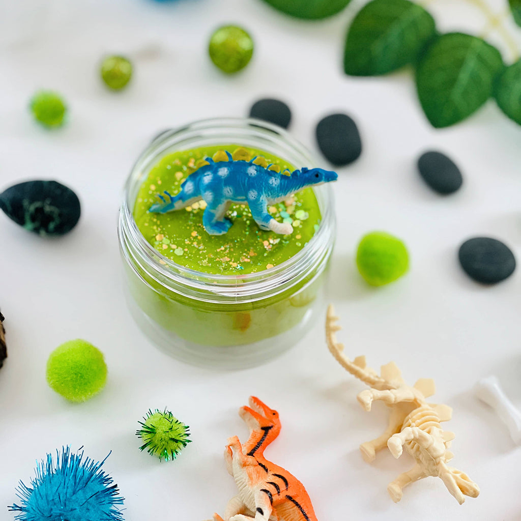 dinosaur sitting on top of green sensory playdough kit jar