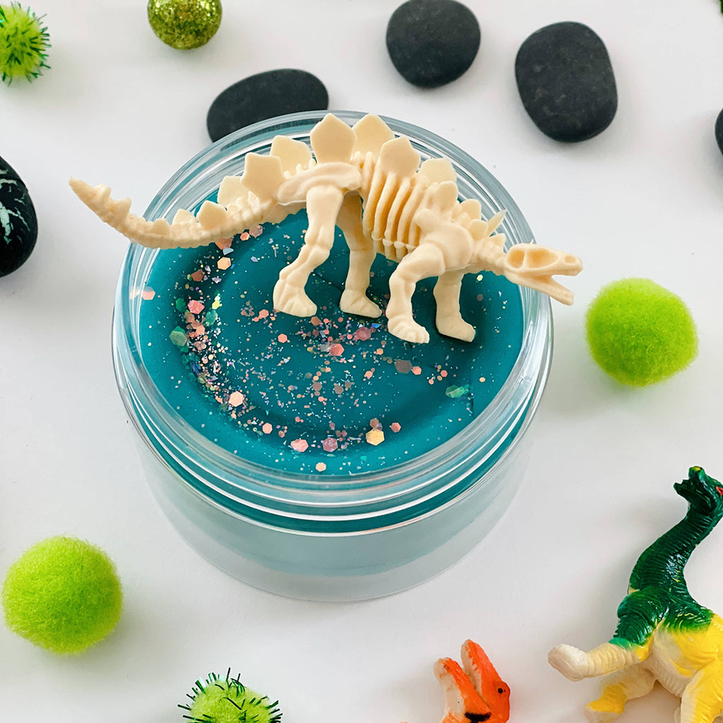 dinosaur skeleton sitting on top of blue scented sensory playdough jar kit