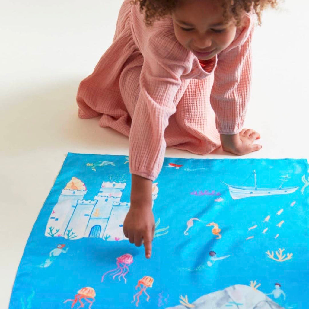little girl playing with an under the sea themed play silk map