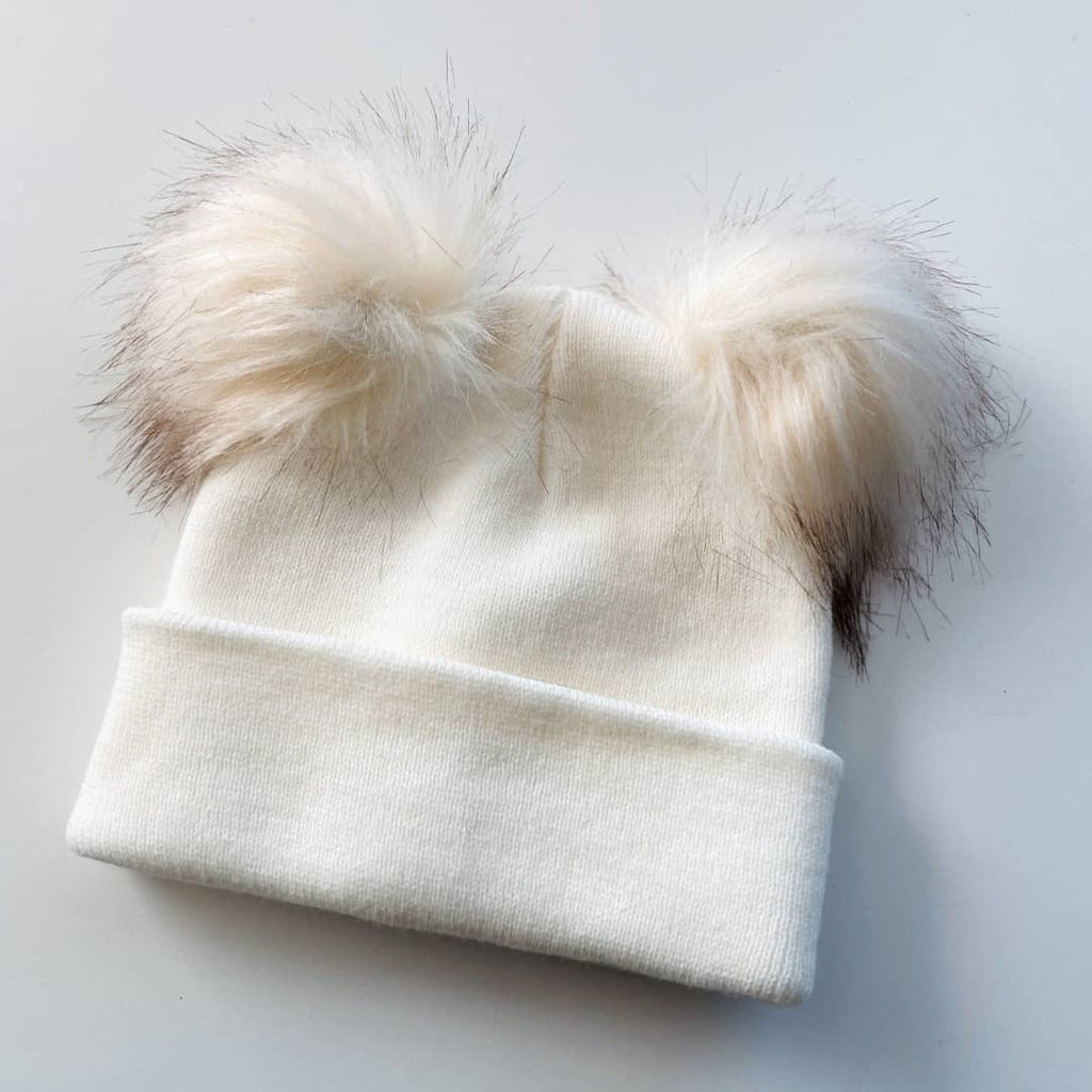 white knitted kids hat with 2 faux fur pom poms on top