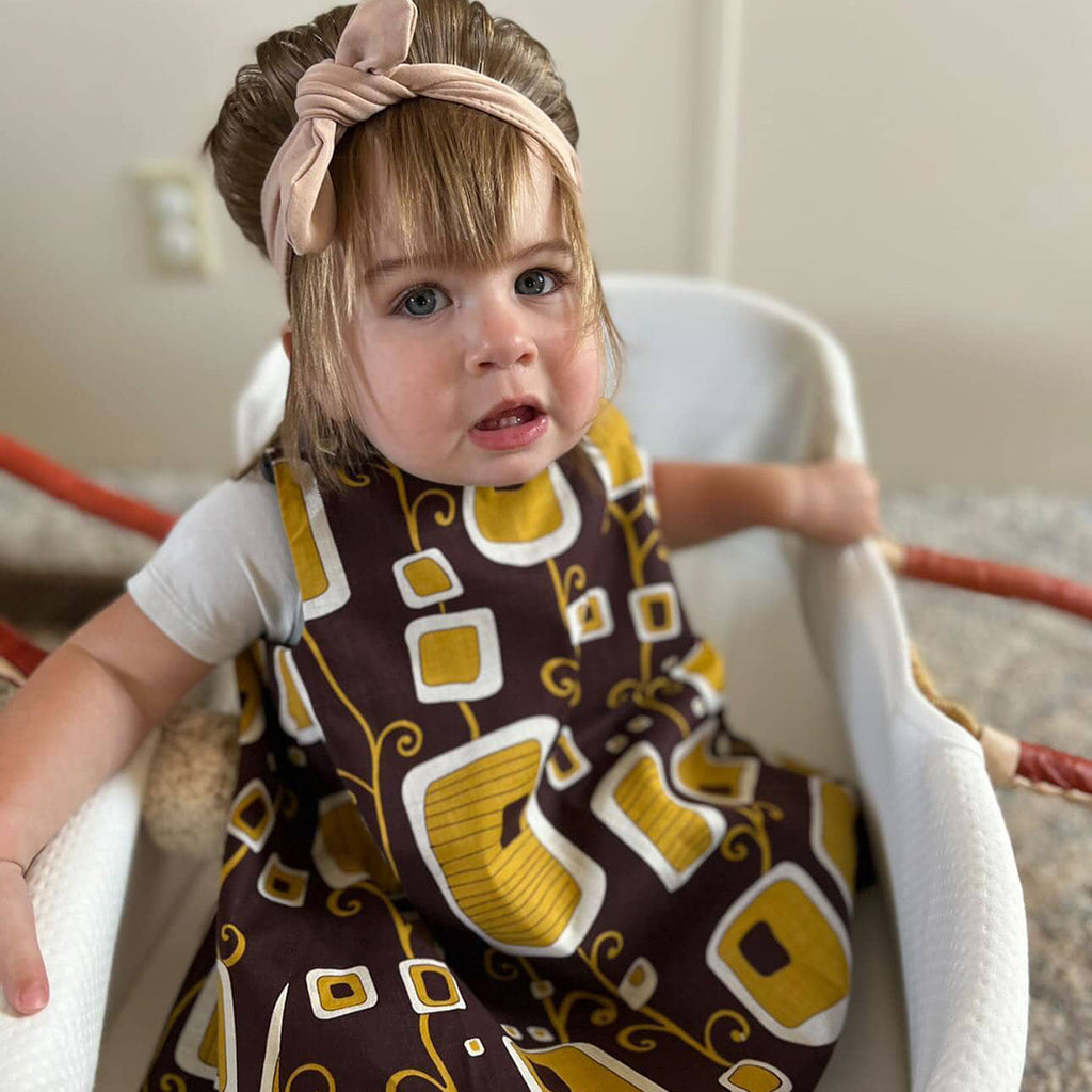 toddler girl wearing a brown reversible pinafore dress
