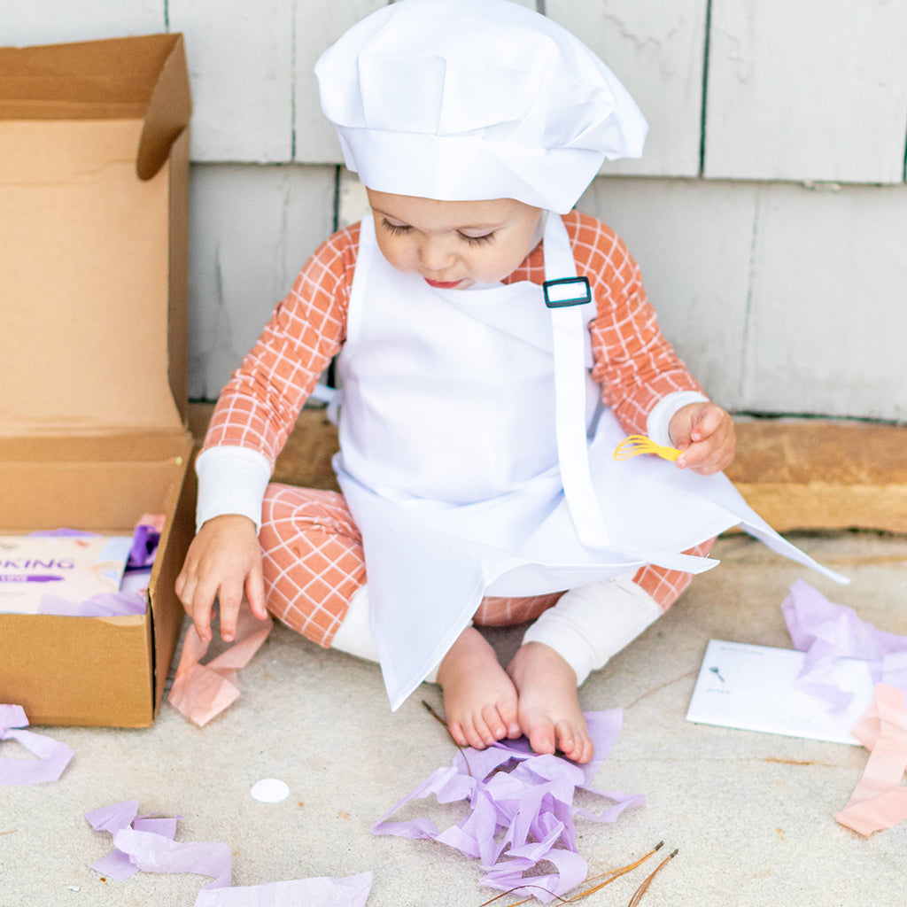 toddler boy wearing a pretend play child's chef hat and apron