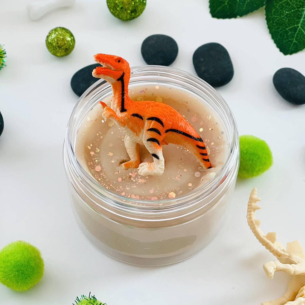 orange dinosaur sitting on top of scented playdough sensory kit jar