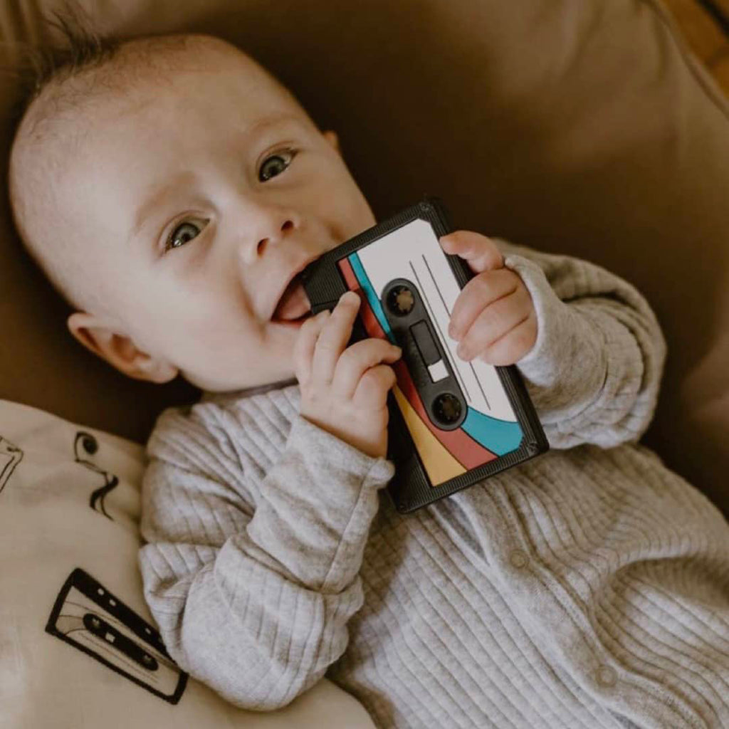 infant holding a retro 80's cassette tape teether