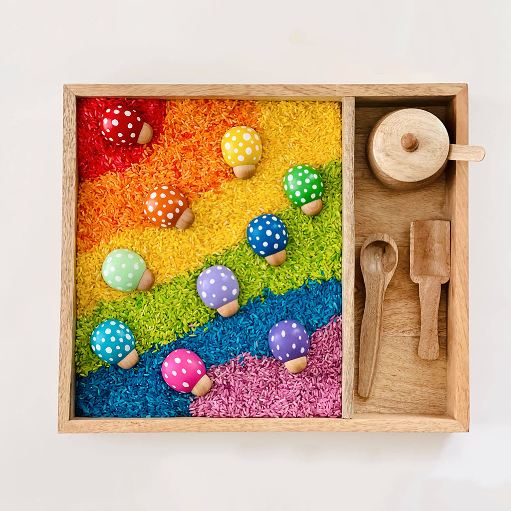 wooden lady bugs inside of a rainbow rice sensory tray