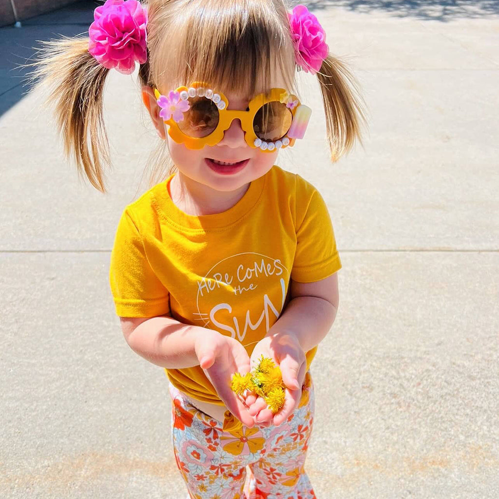 little girl wearing a yellow Here Comes The Sun shirt