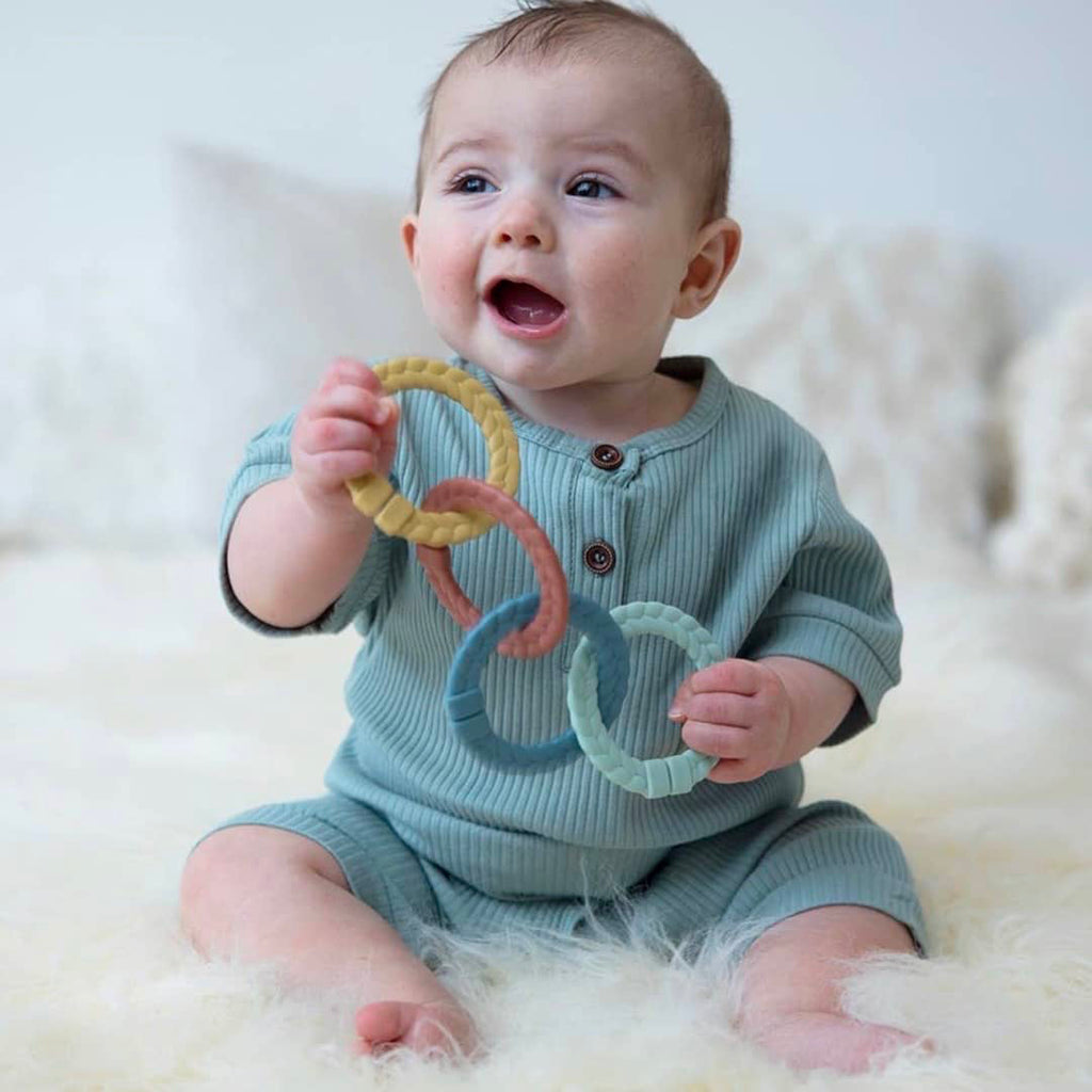 infant boy playing with a set of activity linking toys