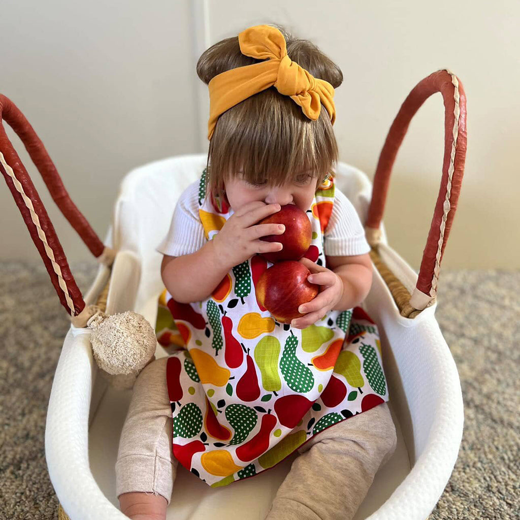 little girl wearing a fall baby dress holding apples