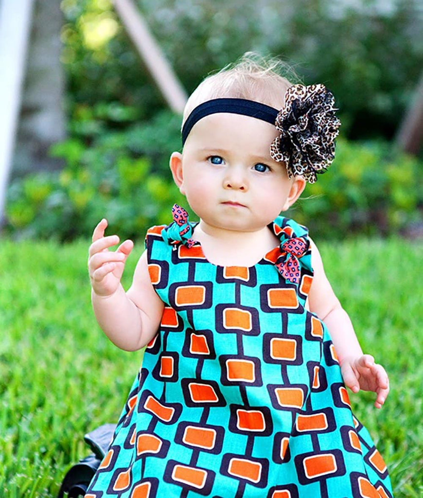 baby gear in a dress with green and orange retro print