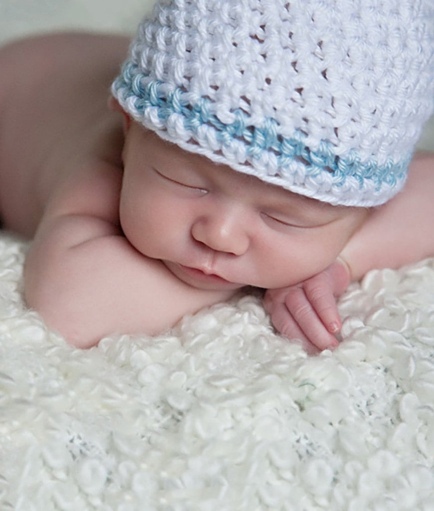 Sleeping newborn wearing a white knit beanie hat